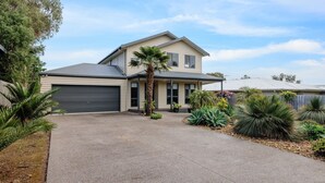 A two-story house with a garage, a covered patio, and a driveway. - The Island's Treasure (Cowes)