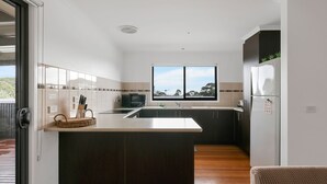 A modern kitchen with a central island, a microwave, and a refrigerator. - The Island's Treasure (Cowes)