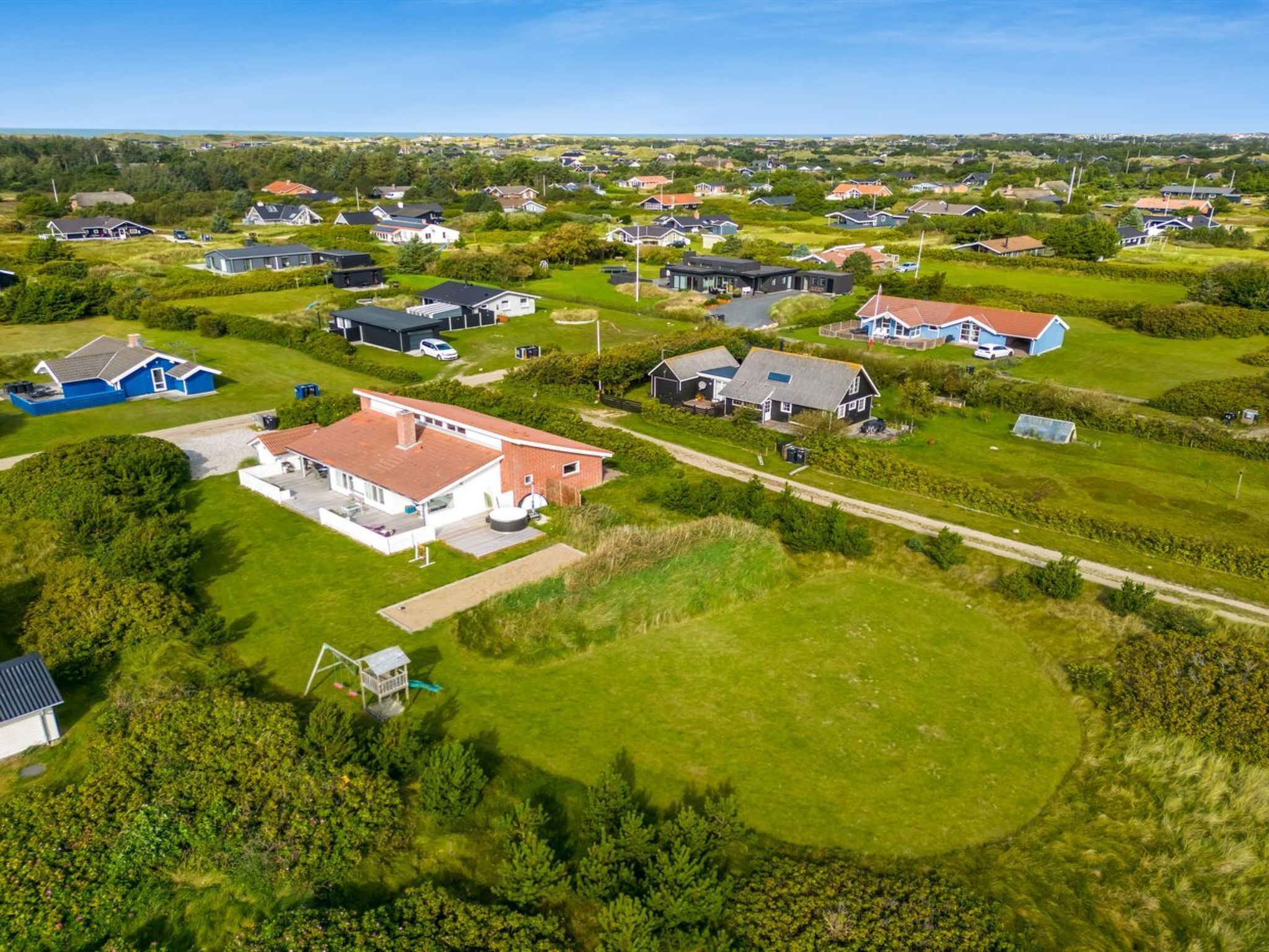 Une vue aérienne d’un quartier résidentiel avec des maisons, des pelouses verdoyantes et un ciel dégagé.