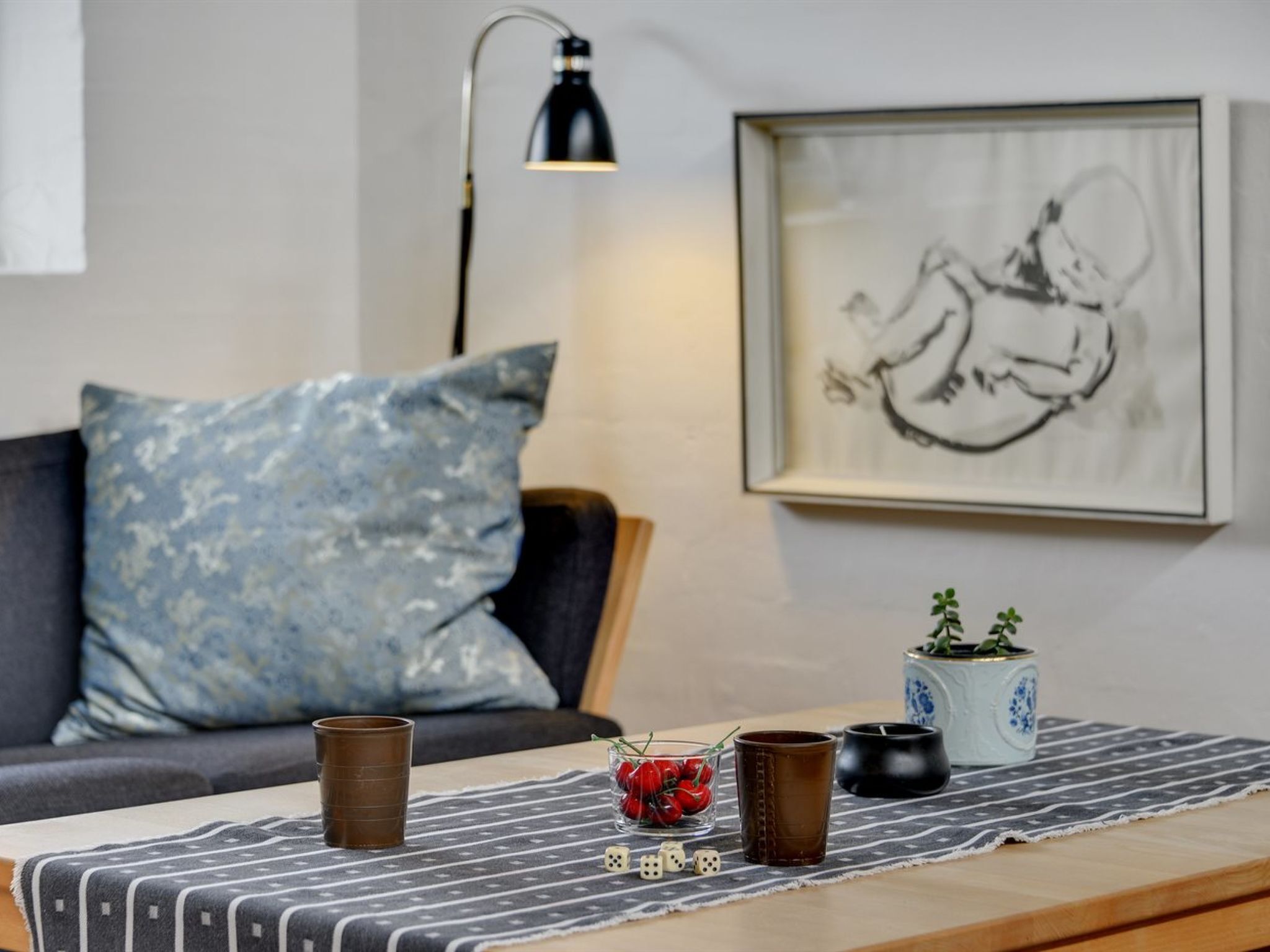 Ein gemütlicher Wohnbereich mit einer Couch, einem Couchtisch, einer Lampe und einem gerahmten Kunstwerk an der Wand.