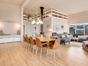 Un vaste espace de vie comprenant une table à manger, des canapés et une cheminée.