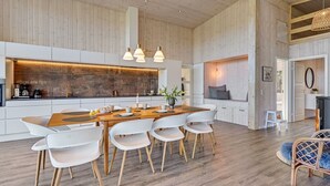 A modern kitchen with a central island, white cabinetry, and a wooden ceiling.