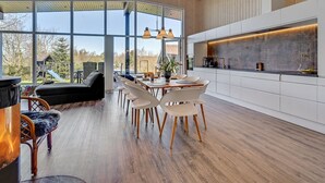A spacious kitchen with a large island, modern pendant lights, and a view of the outdoors.