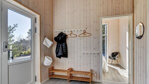 A modern interior with a wooden wall, a bench, a coat rack, and a mirror.