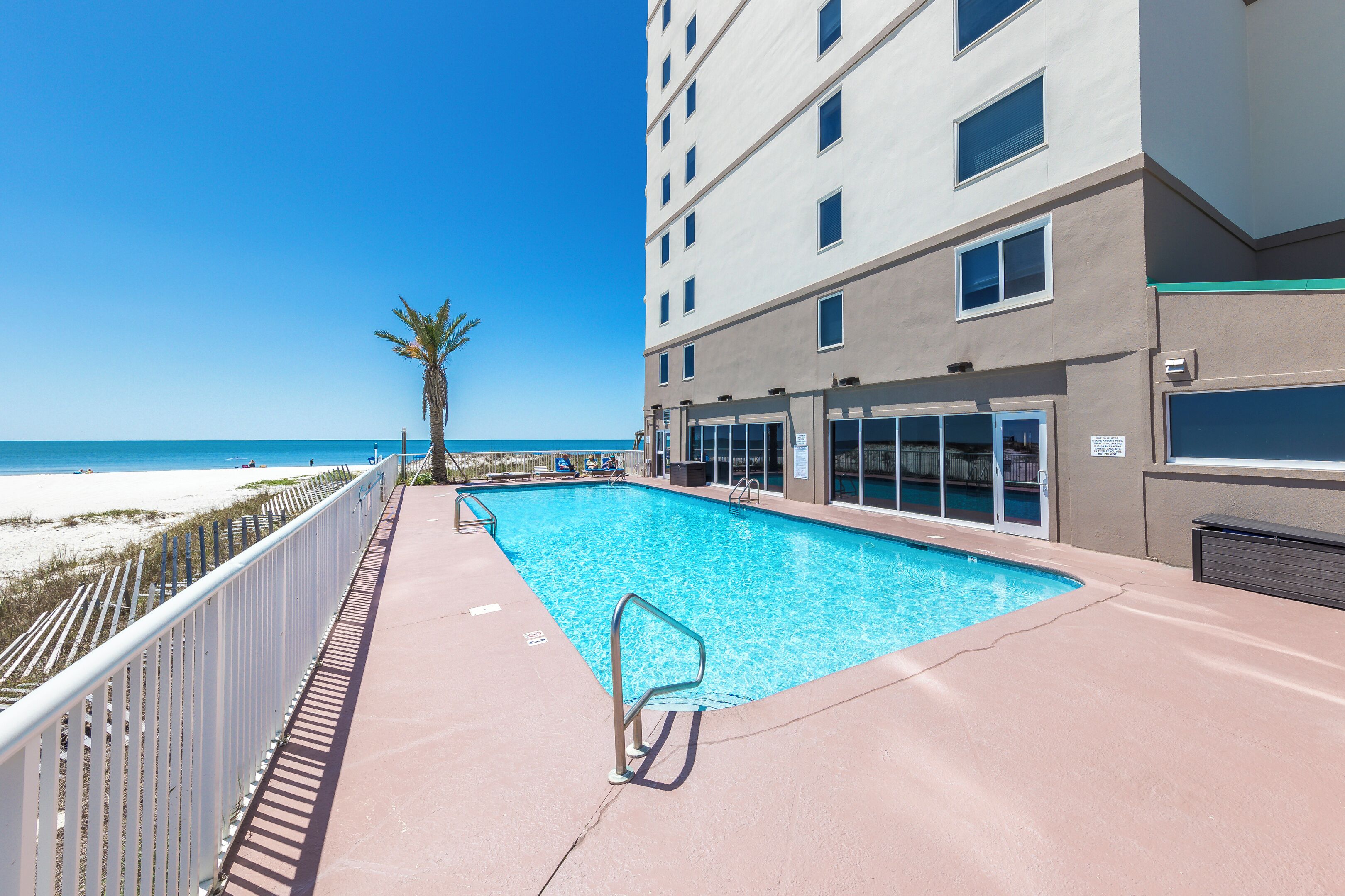 Una piscina junto a la playa, con un edificio al fondo.