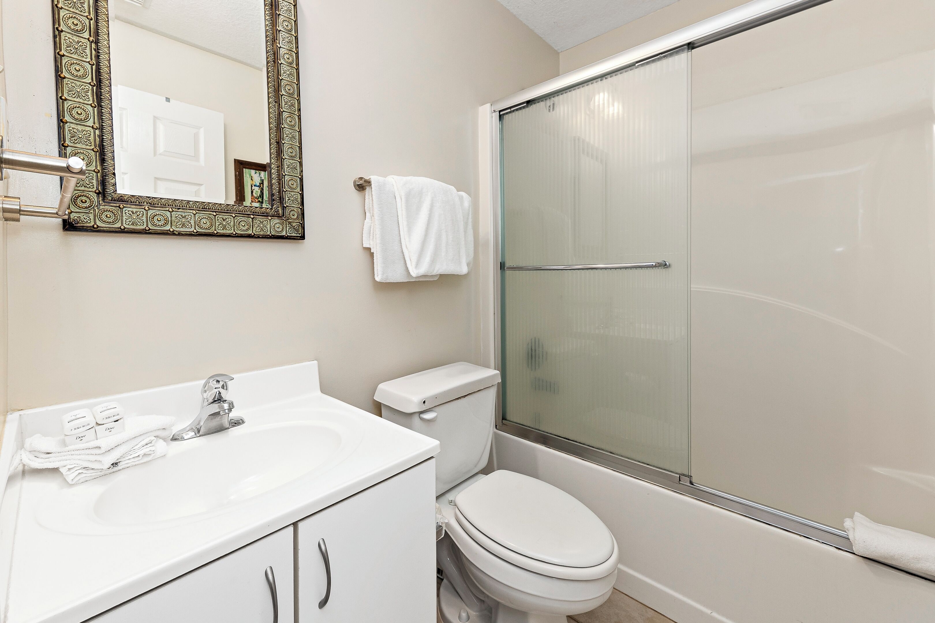 Une salle de bain avec un lavabo, des toilettes et une douche, le tout de couleur blanche.