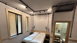 A compact hotel room with a single bed, a small bedside table, a mirror, and a window with blinds. - ART HOTEL 158 (Sofia)