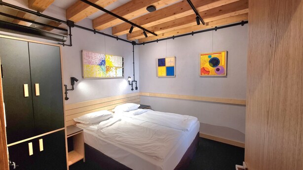 A bedroom with a bed, a wardrobe, and two abstract paintings on the wall. - ART HOTEL 158 (Sofia)