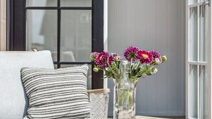 Une table en bois avec un vase en verre et une bougie, un coussin à rayures et une fenêtre en arrière-plan.
