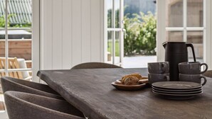 Un coin repas avec une table dressée pour deux personnes, une bouilloire et une assiette de pain.