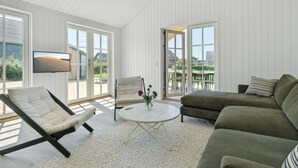 Un vaste espace de vie doté d’un plafond blanc, de grandes fenêtres et d’une vue sur l’extérieur.