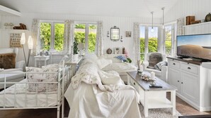 Quarto espaçoso com uma cama grande, uma escrivaninha, televisão e vista para o verde lá fora.