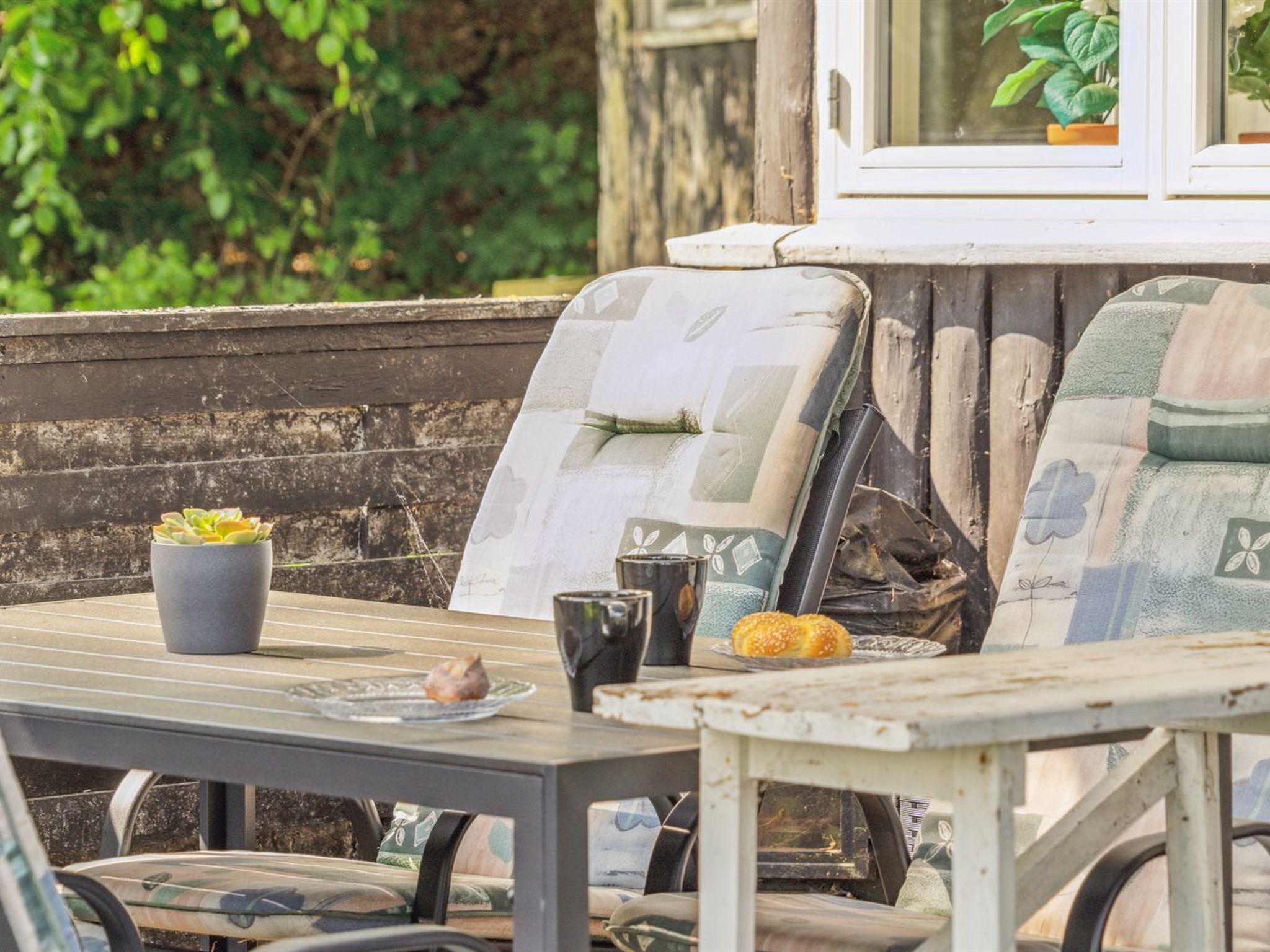 Un espace extérieur aménagé dans un style rustique, avec une table, des chaises et une plante en pot.