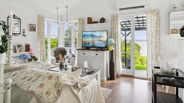 Quarto com cama, televisão, escrivaninha e vista para o verde lá fora.