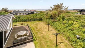 Ein Küstenanwesen mit einer Terrasse, einem Tisch und Stühlen und Blick aufs Meer.