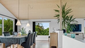 Ein moderner Essbereich mit Holzboden, großen Fenstern und Blick auf Grünflächen.
