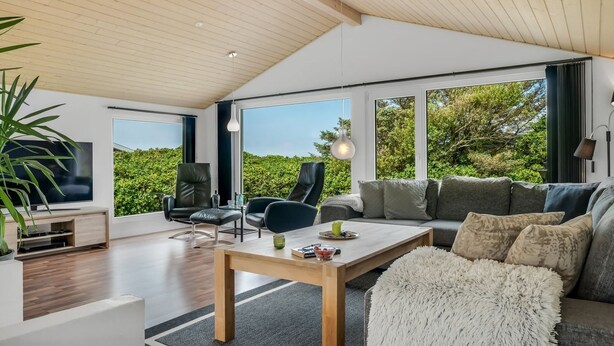 Ein geräumiges Wohnzimmer mit großem Fenster, Holzboden und einem modernen Sofa.