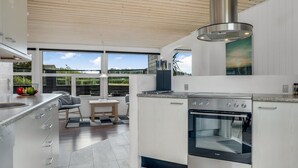 Eine moderne Küche mit großem Fenster, integriertem Backofen und einem Essbereich mit Tisch und Stühlen.
