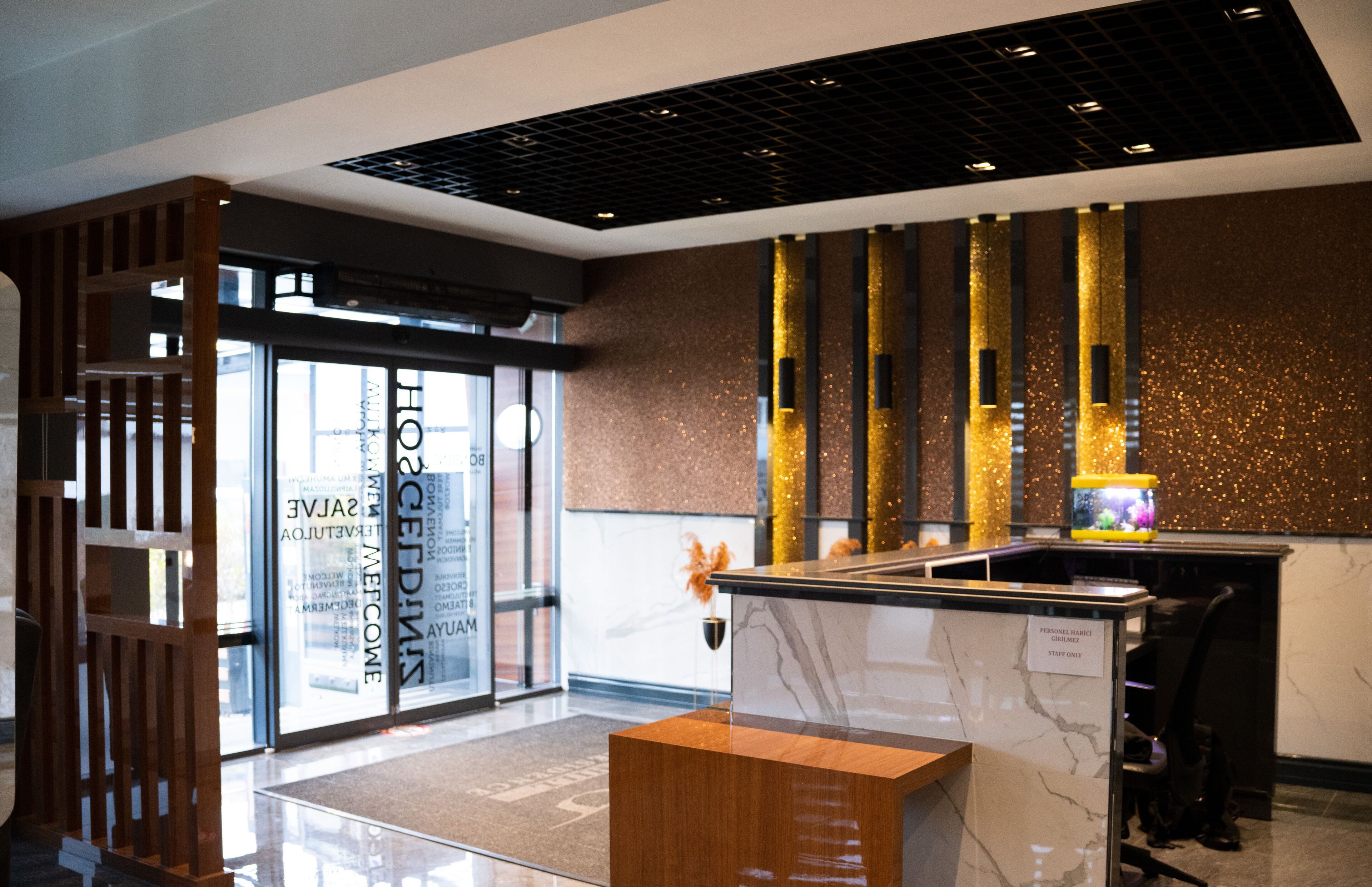 A reception desk with a marble top, a wooden partition, and a decorative fish tank.