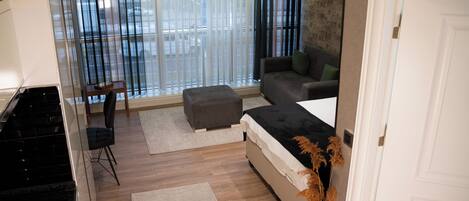 A modern living room with a sofa, ottoman, and a dining area with a table and chairs.
