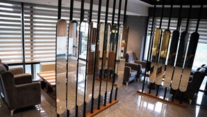 A modern interior with a reception desk, seating area, and a decorative partition with mirrors. - MG Hill Hotel (Malatya)