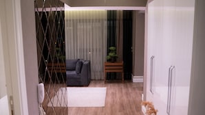 A modern interior with a sofa, a small table with a plant, and a wardrobe. - MG Hill Hotel (Malatya)