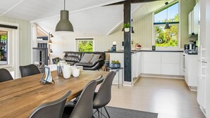 Een moderne keuken met witte kastjes, een houten eettafel en zwarte stoelen.