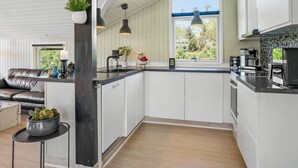 Een moderne keuken met witte kasten, een zwart aanrecht en hanglampen.