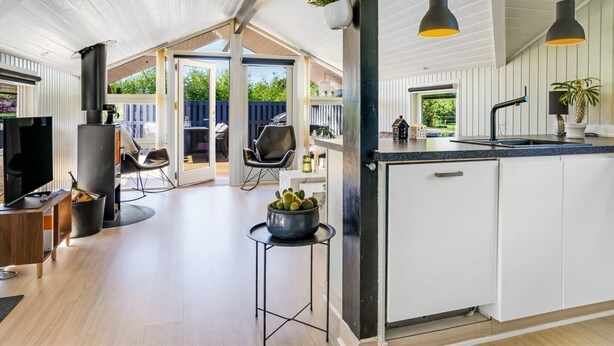 Een moderne keuken met een groot eiland, een eethoek met stoelen en uitzicht op de omgeving.