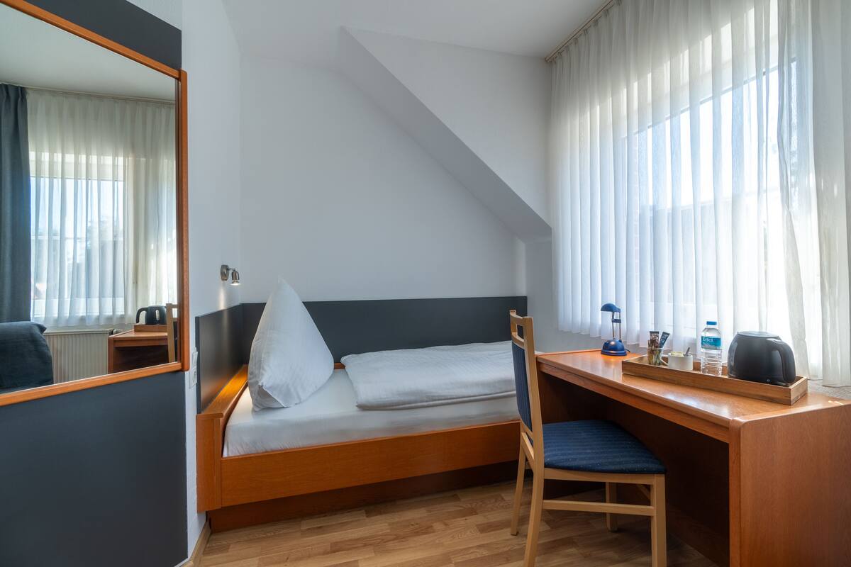 A compact room with a bed, a desk, and a chair.