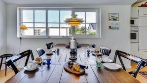 Ein Esszimmer mit Holztisch, Stühlen und einer Pendelleuchte.