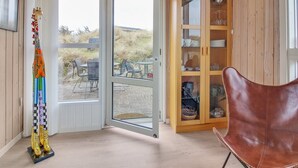 Une pièce avec un plafond en bois, une porte vitrée donnant sur l’extérieur, un fauteuil en cuir marron et un meuble avec des portes en verre.