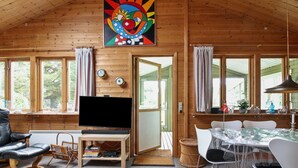 A wooden cabin interior with a TV, seating, and a dining area.