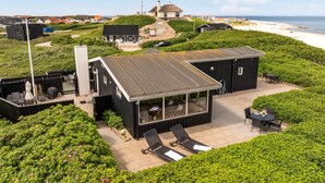 A coastal property with a modern house, outdoor seating, and a view of the beach.