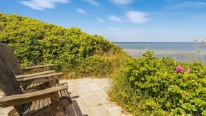 A wooden bench on a stone pathway with a view of the sea and a clear sky.