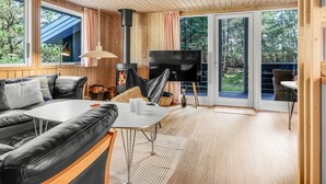Un intérieur de chalet moderne avec un canapé, un téléviseur et un poêle à bois.