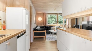 Une cuisine de taille réduite avec des meubles blancs, un plan de travail noir et un plafond en bois.