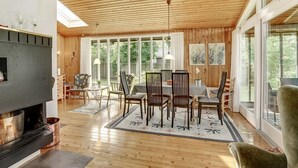 Un salon spacieux avec un plafond en bois, de grandes fenêtres, une cheminée et un coin repas.