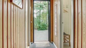 Un couloir en bois avec une porte donnant sur un espace extérieur arboré.