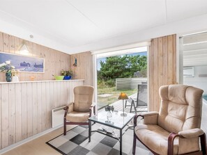 Een modern interieur met twee leren fauteuils, een glazen tafel en uitzicht op het omliggende landschap.