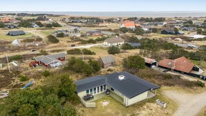 A residential area with houses, a clear sky, and a body of water in the background.