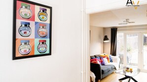 A living room with a sofa, a coffee table, and a framed picture of jars on the wall. - Flexible 2-Bed House: Ideal for Business Trips (Northampton)