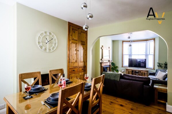 Un comedor con una mesa de madera, sillas y un reloj fijado a la pared.