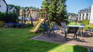 A playground with a slide, swings, and a table with chairs in a grassy area.