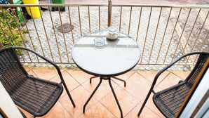 A small outdoor patio with a round table and two wicker chairs.