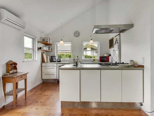 A modern kitchen with a large island, wooden flooring, and white cabinetry.