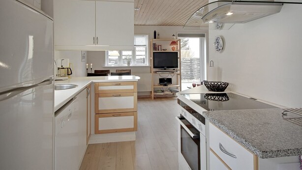 A modern kitchen with white cabinetry, a wooden ceiling, and a built-in TV.