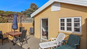 A small patio area with a table and chairs, a covered umbrella, and a sliding door leading to an interior space.