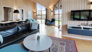 Een moderne woonkamer met een zwarte leren bank, een ronde salontafel en een televisie op een meubel.