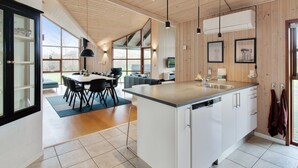 Een moderne keuken met een centraal eiland, een houten plafond en grote ramen.